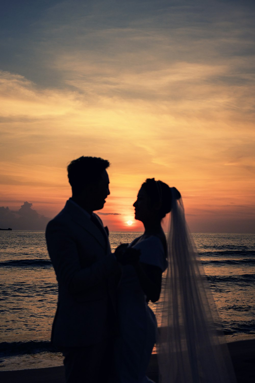 a man and woman kissing on a beach at sunset