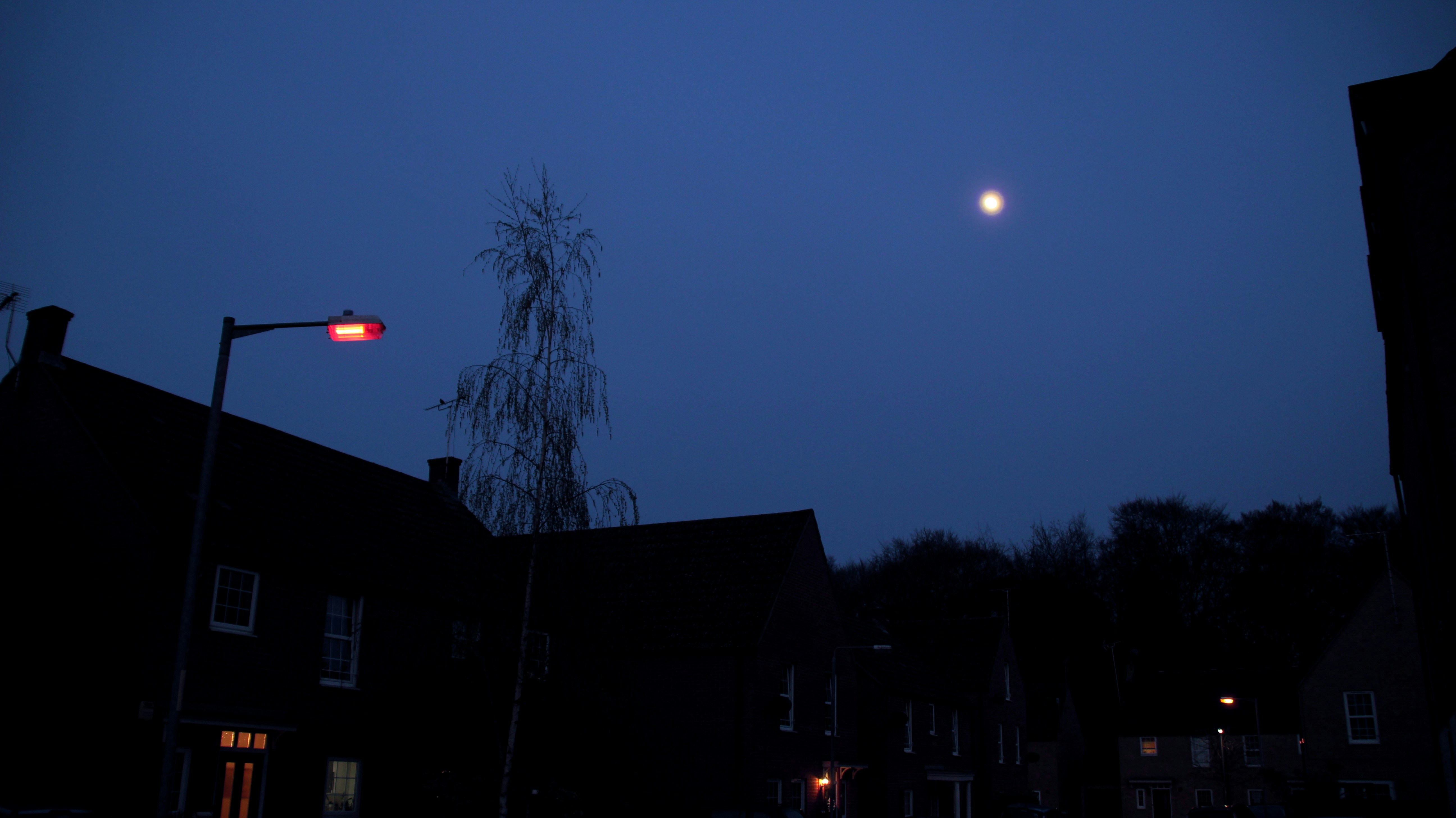 a moon in the sky over houses