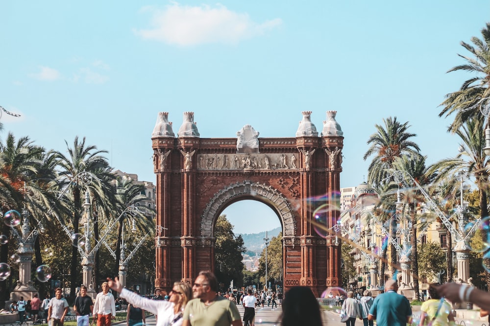 a group of people standing in front of a crowd with Arc de Triomf in the background
