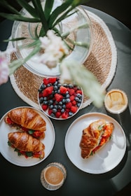 A colorful brunch table with coffee, salads, sandwiches, and fresh fruit.