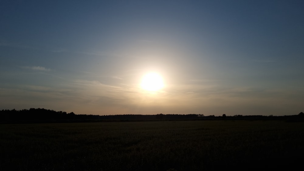 a field with the sun in the background