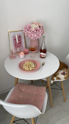 a dog sitting at a table with food and drinks on it