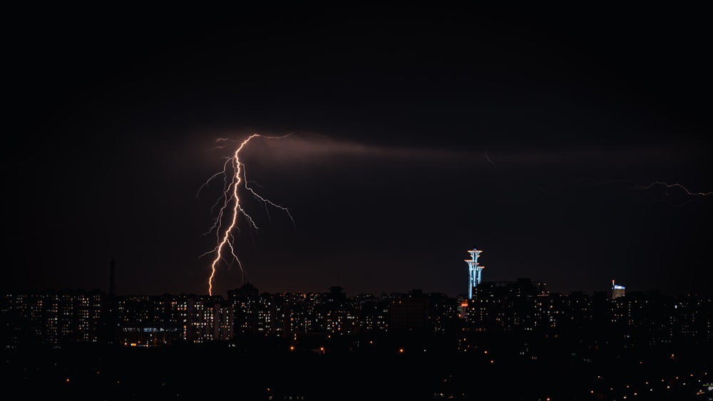 a city skyline at night with lightning striking the ground