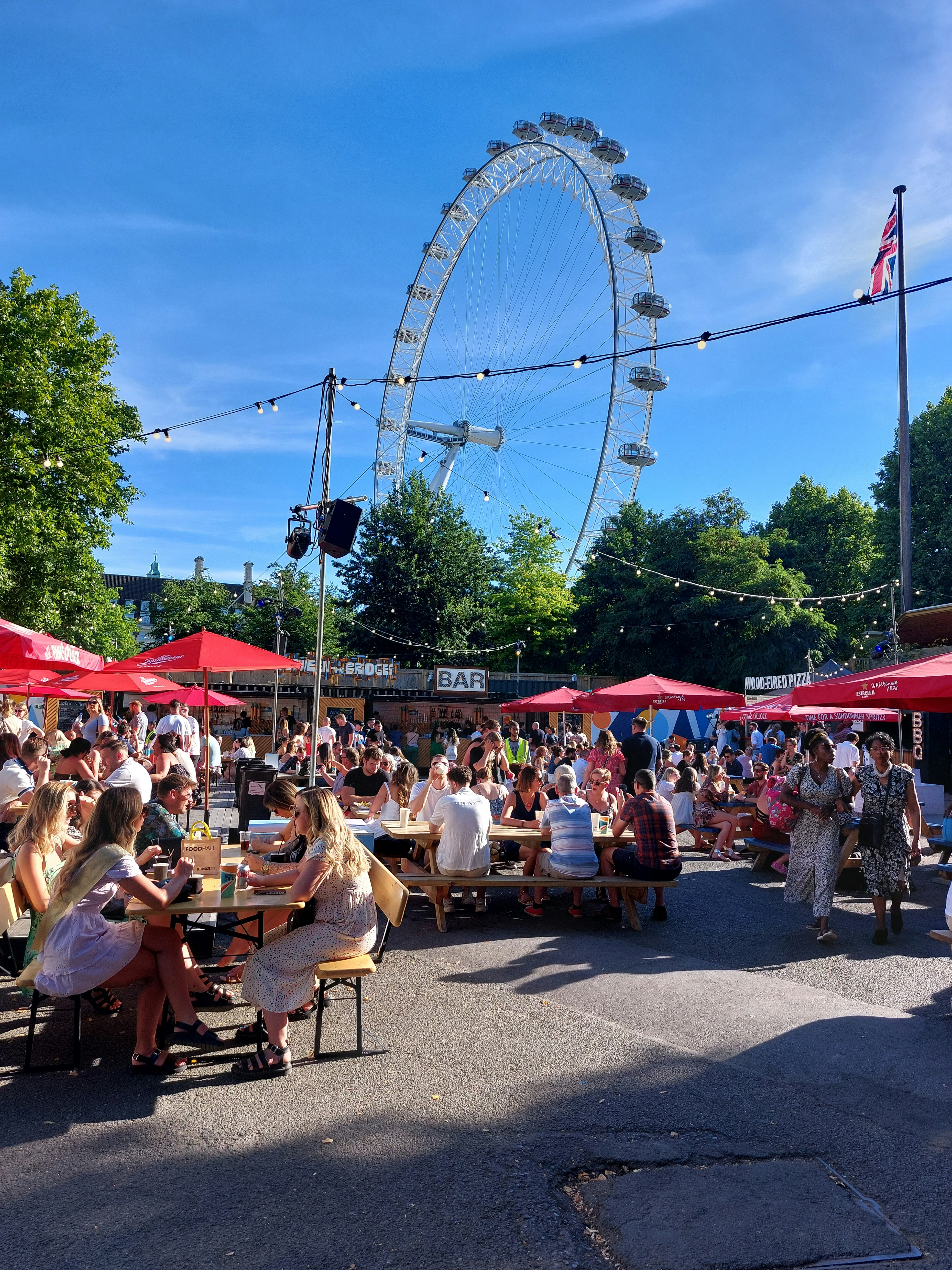 Un groupe de personnes assises à des tables devant une grande roue ...