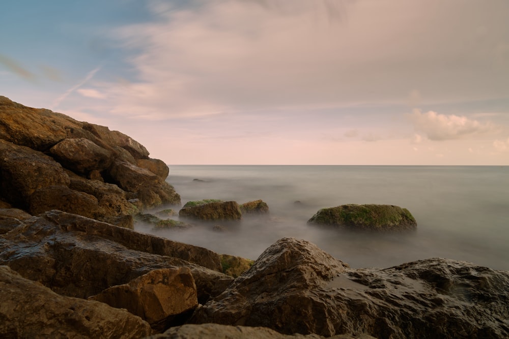 a rocky beach with a body of water in the background