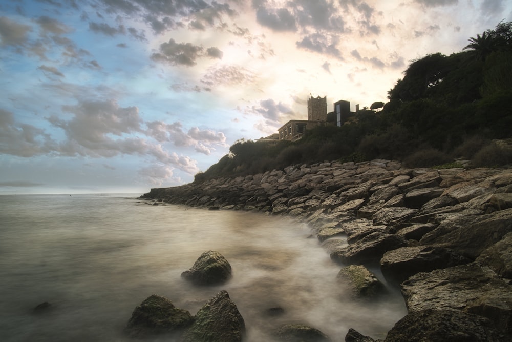 a rocky beach with a building on the shore