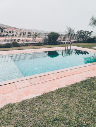 a pool with a brick wall and a brick walkway with a building in the background