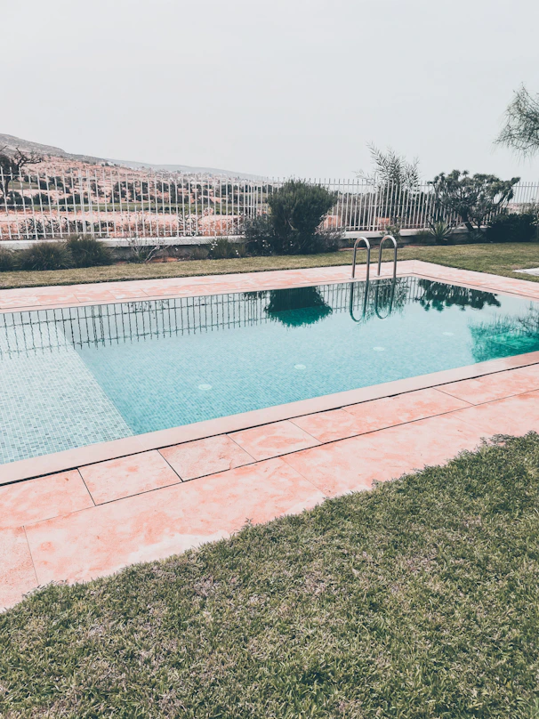 a pool with a brick wall and a brick walkway with a building in the background