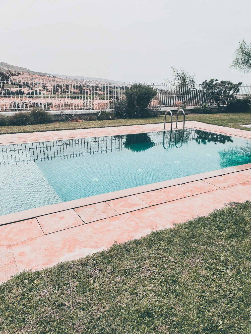 a pool with a brick wall and a brick walkway with a building in the background