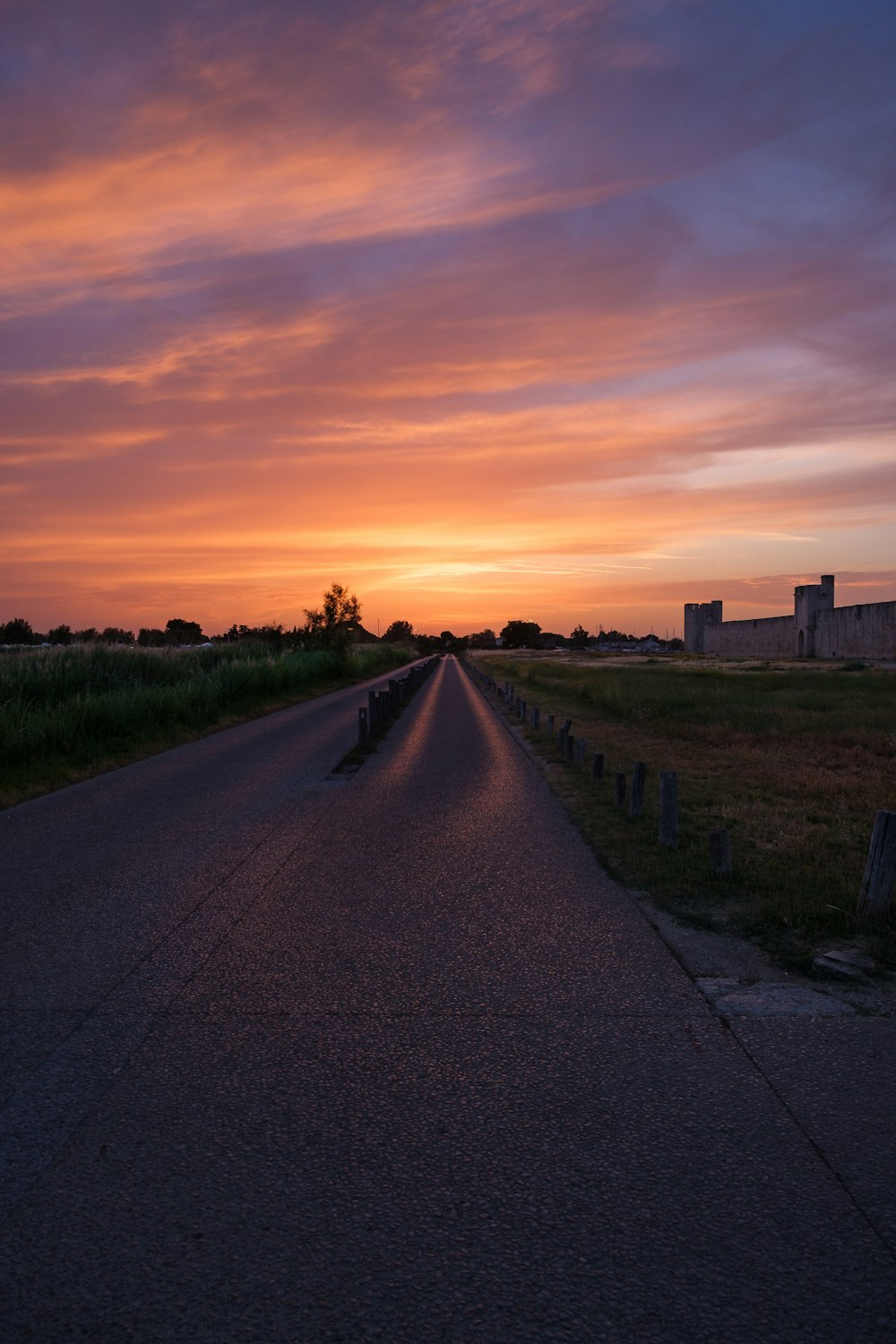 a road with grass and a sunset