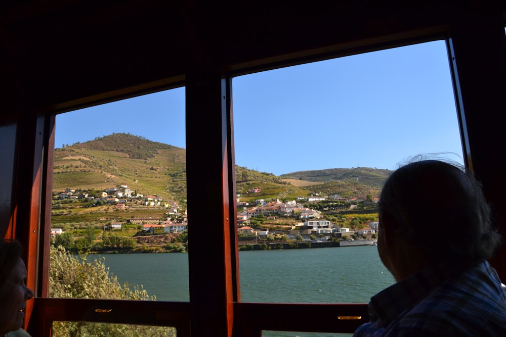 a person looking out a window at a town and water