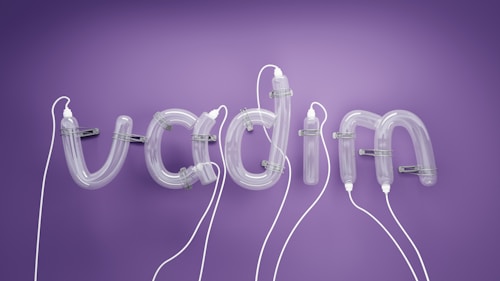 Curled tubes form the letters spelling 'vacuum' against a soft purple background. The glass-like tubes have mechanical clips and wires connecting them, giving an industrial and modern feel.