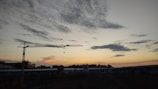 Close-up of hands shaking in front of a construction crane during sunset.