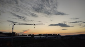 Close-up of hands shaking in front of a construction crane during sunset.