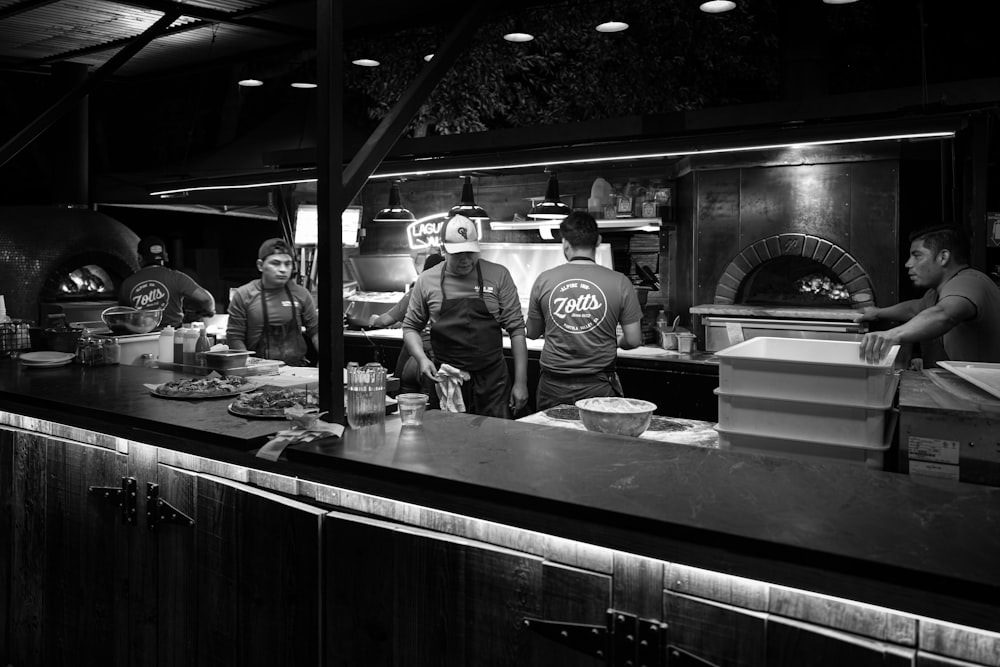 a group of people stand in a kitchen