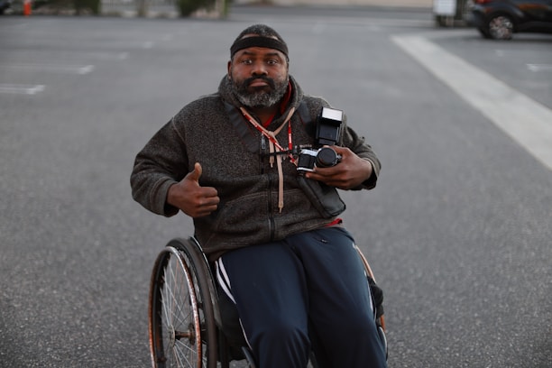 a man in a wheelchair pointing a camera