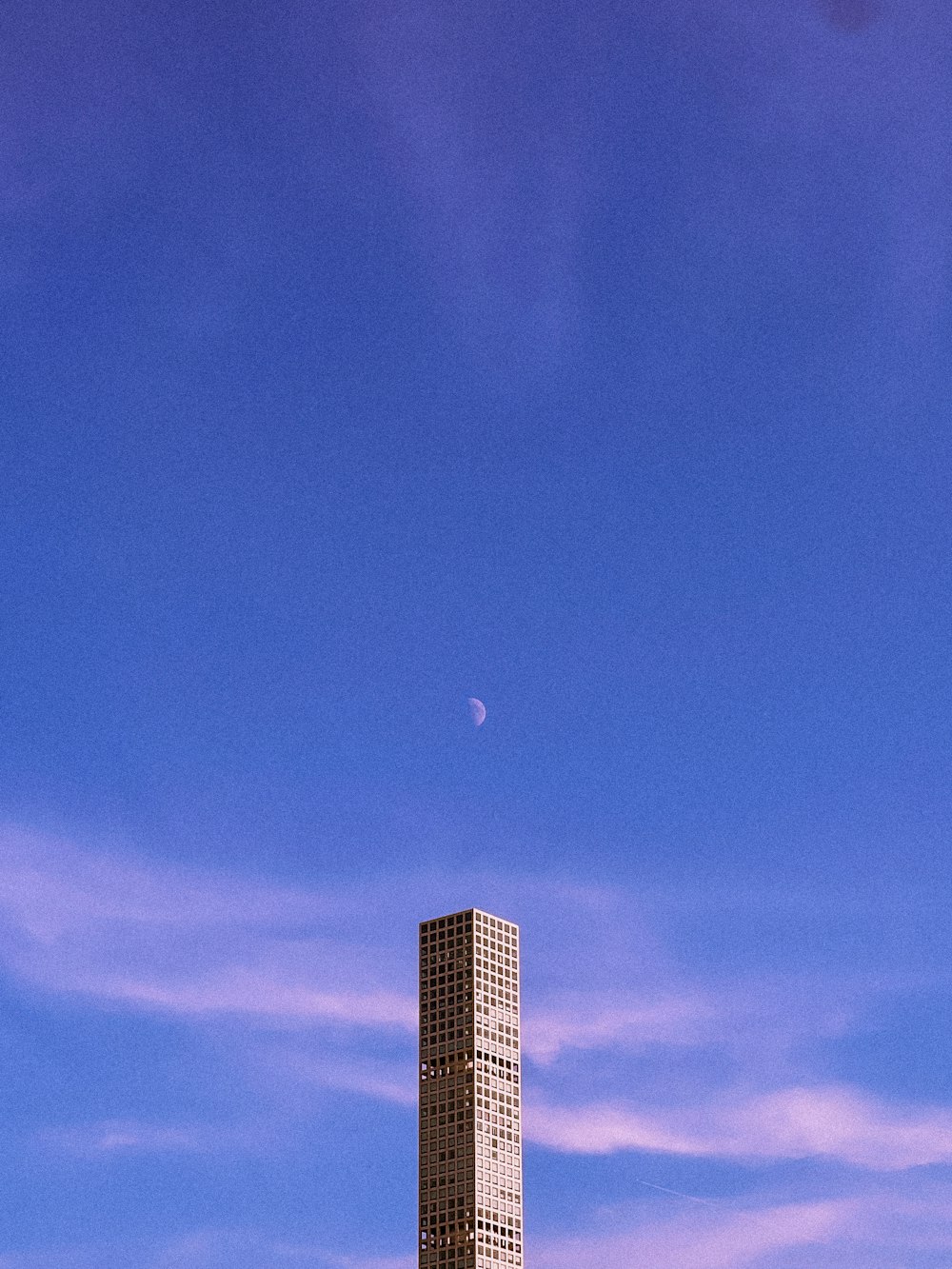 a tall building with a moon in the sky