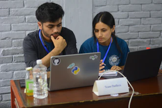 Consultants collaborating over laptops with code and flowcharts on screens.