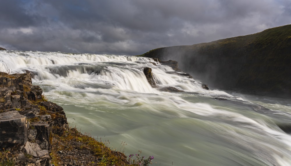 a waterfall with rocks and grass