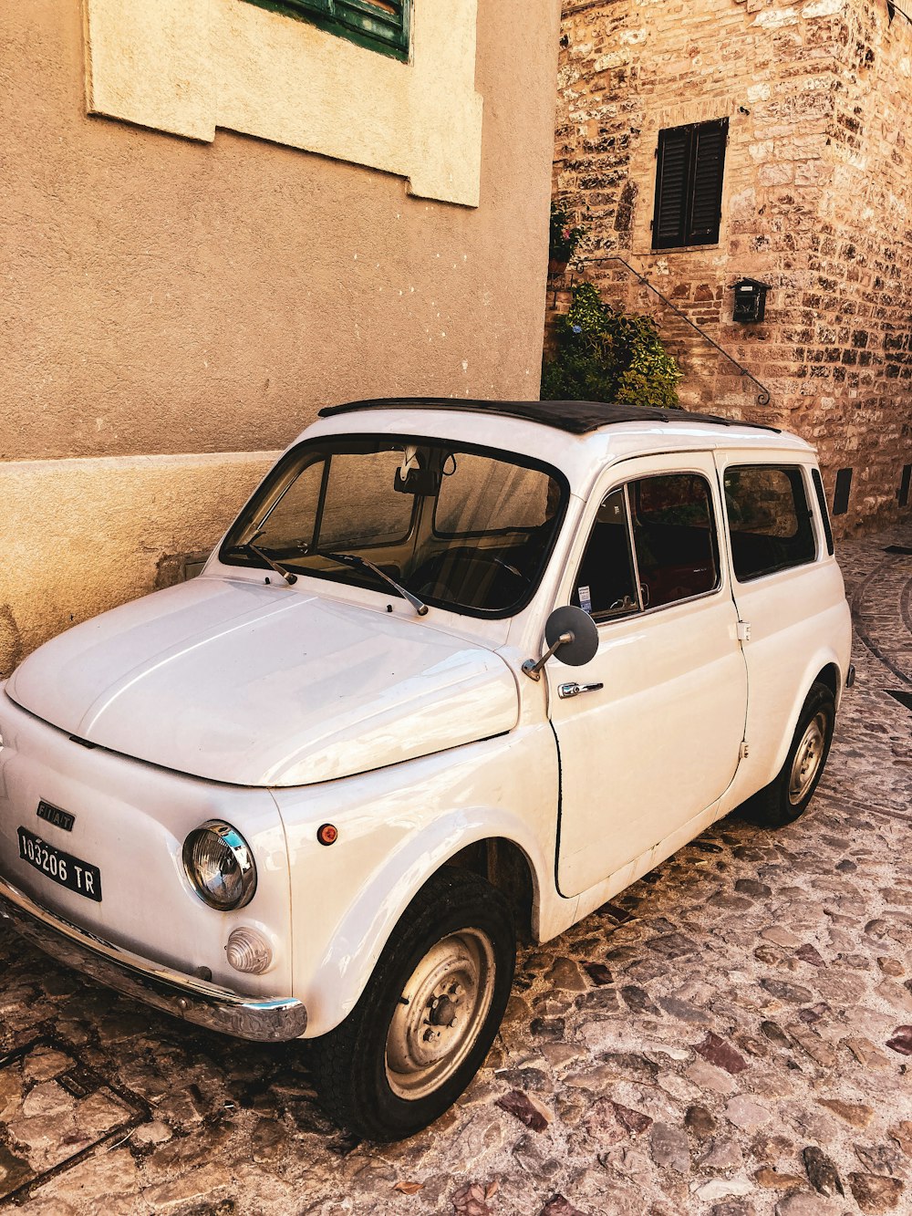 a white car parked on a cobblestone road