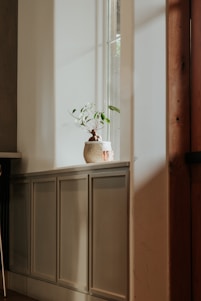 A serene minimalist living room bathed in natural light with plants and soft, neutral tones.