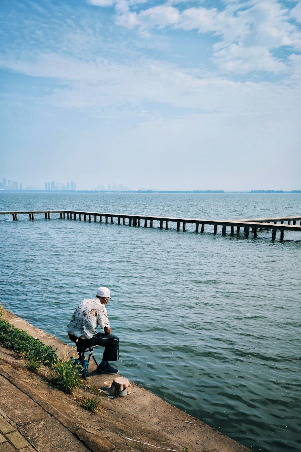 a man sitting on a bench by a body of water