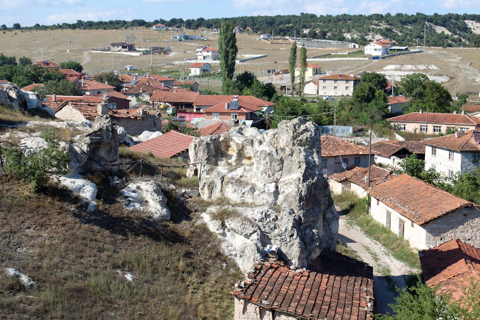 Village nestled at hill's foot with stone or brick houses and red-tiled roofs
