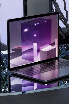 A sleek, reflective laptop displaying a digital artwork of geometric shapes and purple lighting. The setting includes a reflective surface that mirrors the laptop and a modern decor background.