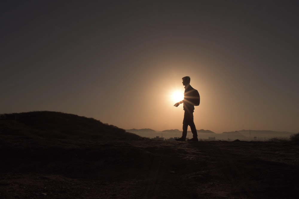 a person standing on a hill with the sun behind them