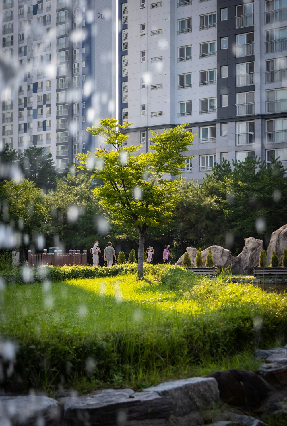 a group of people walking around a park in front of a building