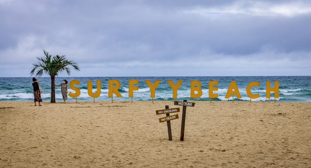 a beach with a sign and a tree