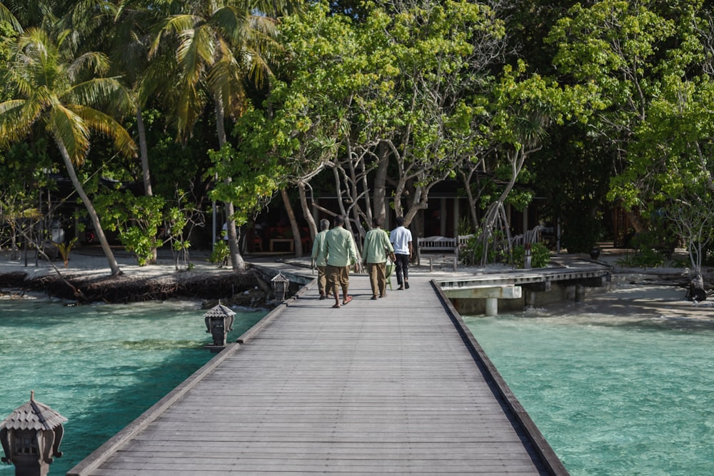 a group of people walking on a wooden walkway over water