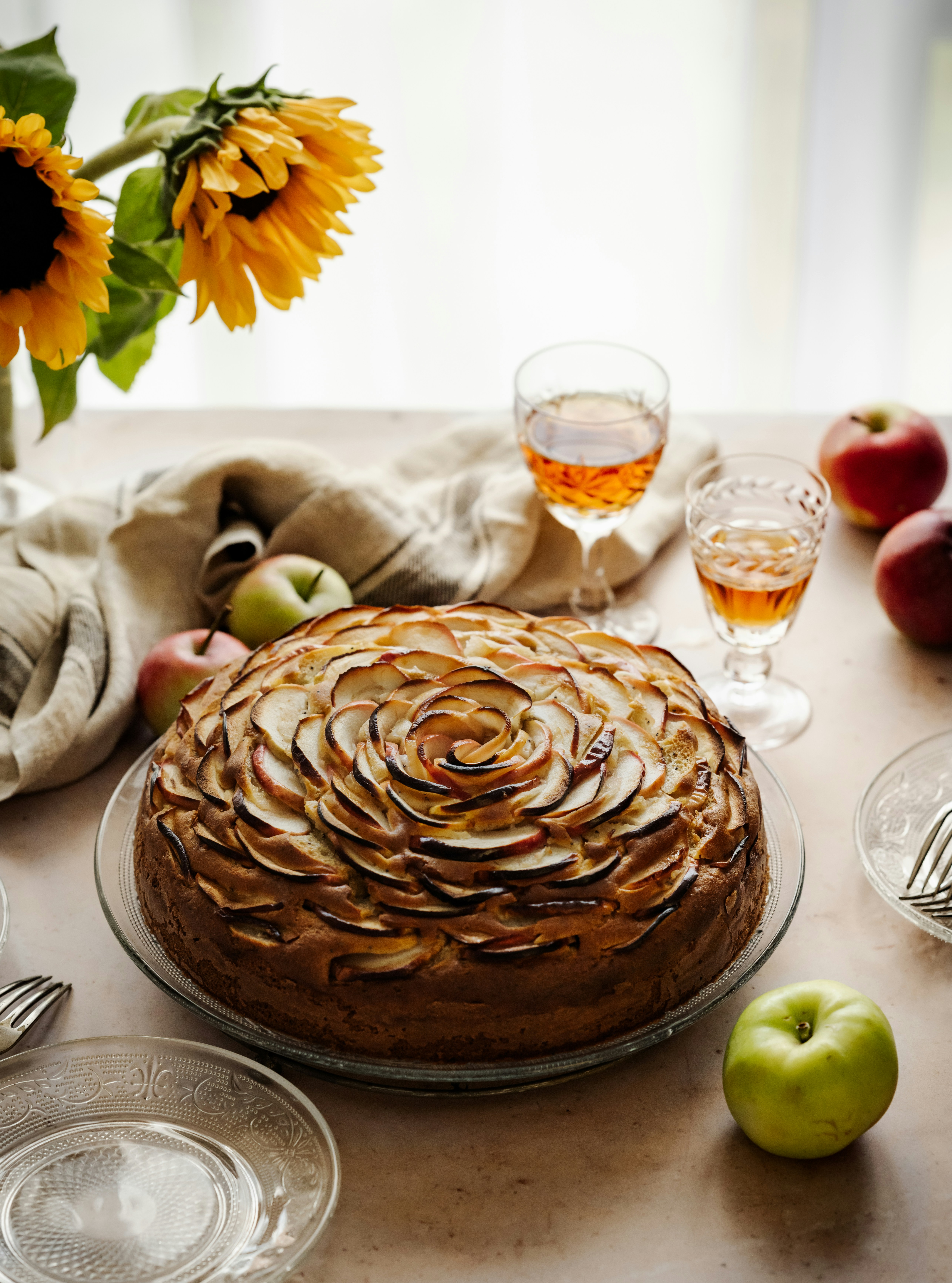 a cake with a brown frosting on a table with fruit and glasses