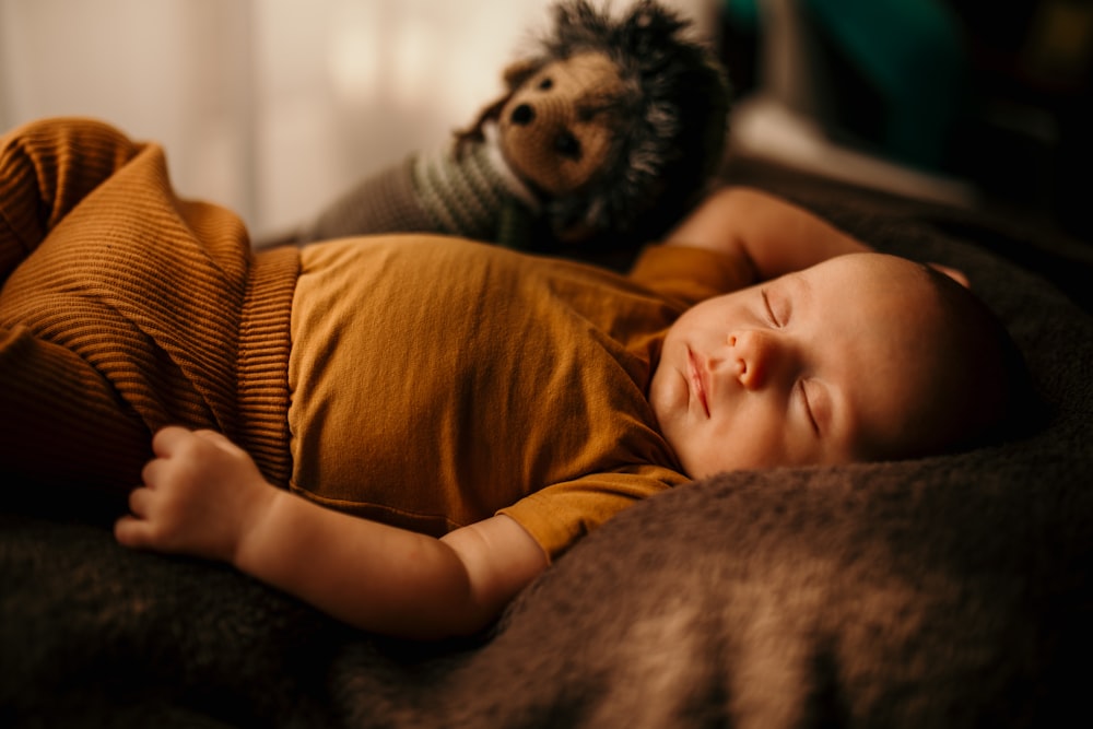 a baby lying on a couch with a dog