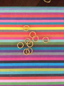 A collection of colorful rings displayed on vibrant red and black fabrics representing Candomblé traditions.