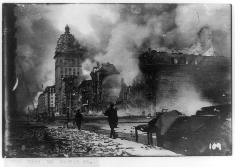 View of street in San Francisco, California, earthquake aftermath with man patrolling with gun.