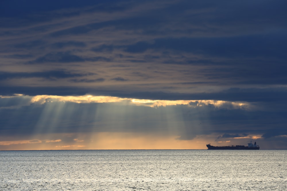 a large body of water with a boat in it and a cloudy sky above