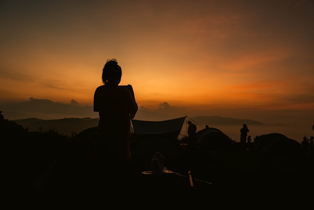une personne debout devant un coucher de soleil