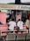 A small eatery with a pink exterior where several people are seated at a counter. The eatery, named 'Mommy J Eatery', is located at a stall and offers special dishes like lomi and silog. Inside, there are various bottles and items on shelves. The seating area includes benches and metal chairs.