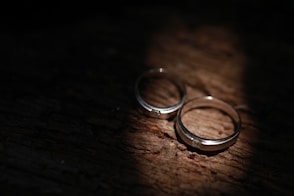 a pair of wedding rings on a wood surface