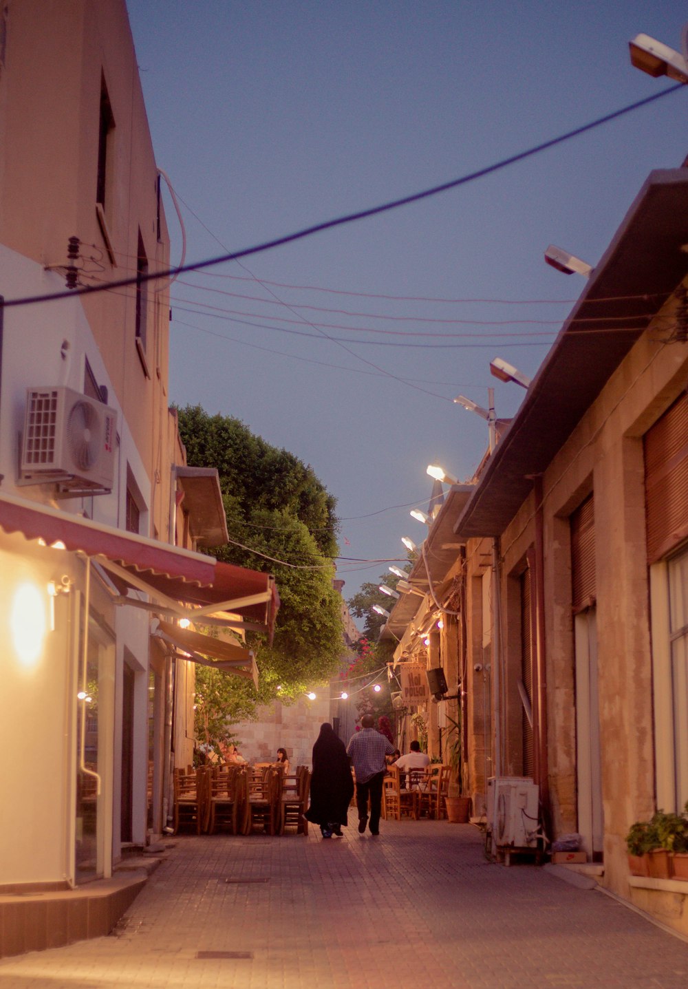 a couple of people walking down a street between buildings