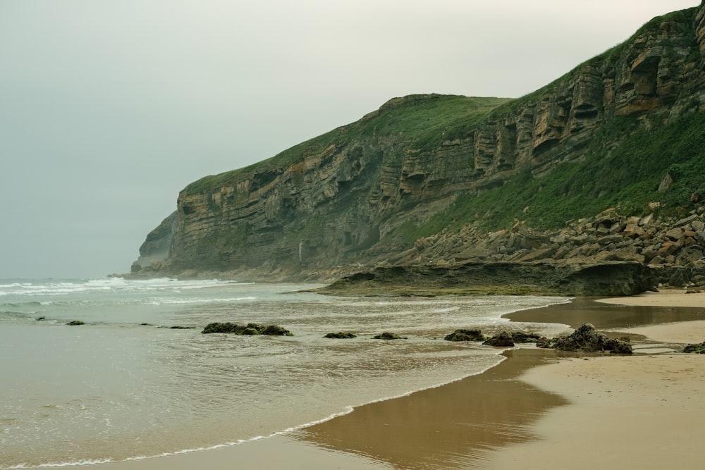 a beach with a cliff in the background