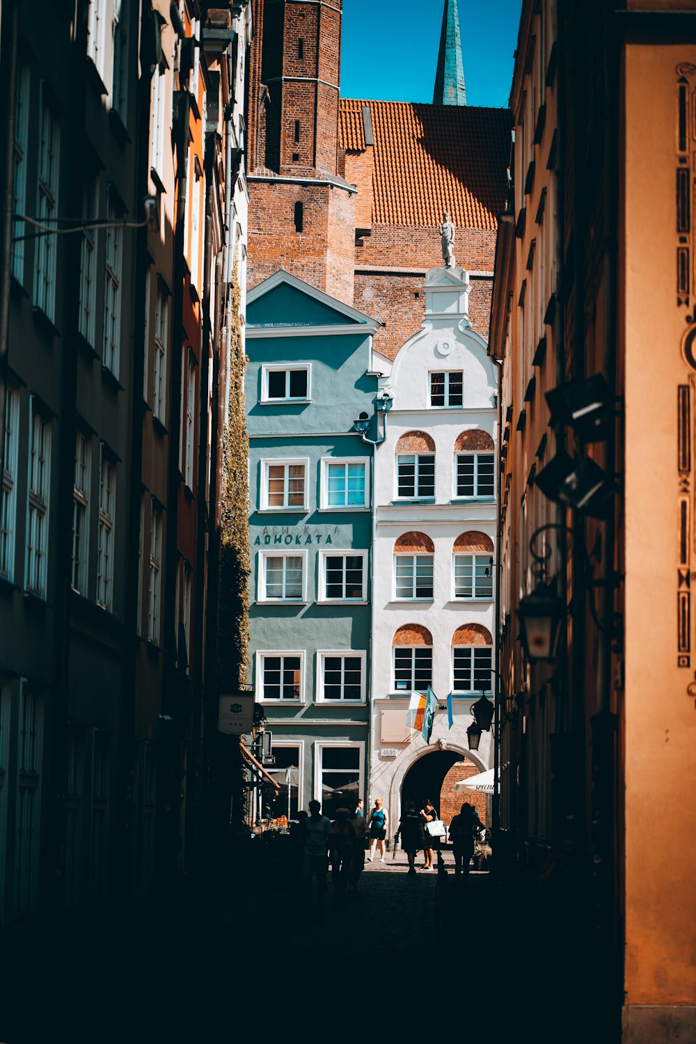 Eine Gruppe von Menschen geht durch eine enge Gasse zwischen Gebäuden