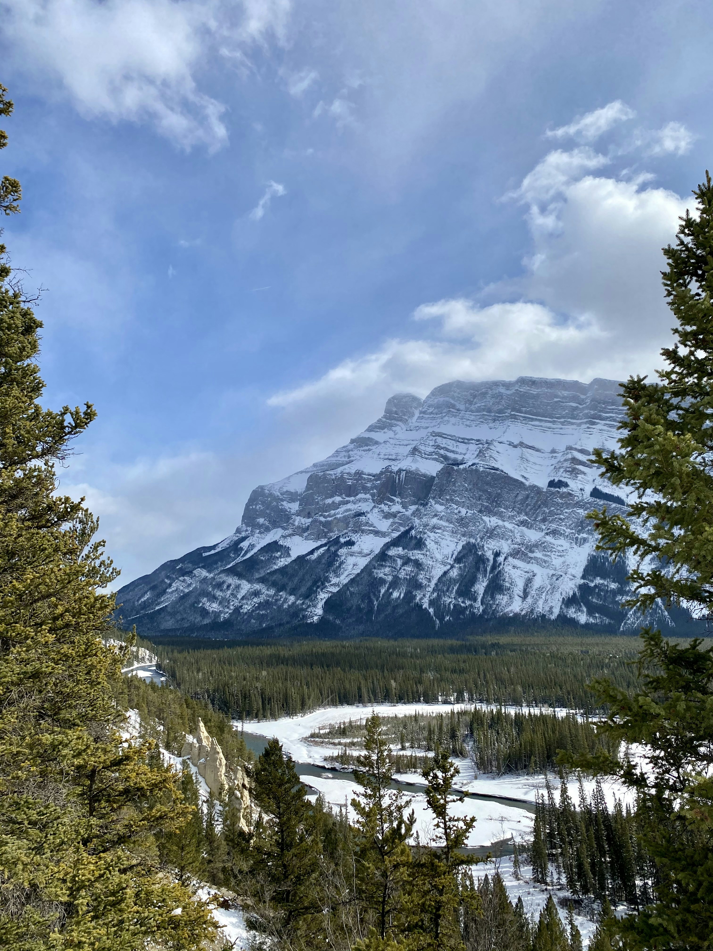 A snowy mountain with trees and a river below photo – Free Canada Image ...