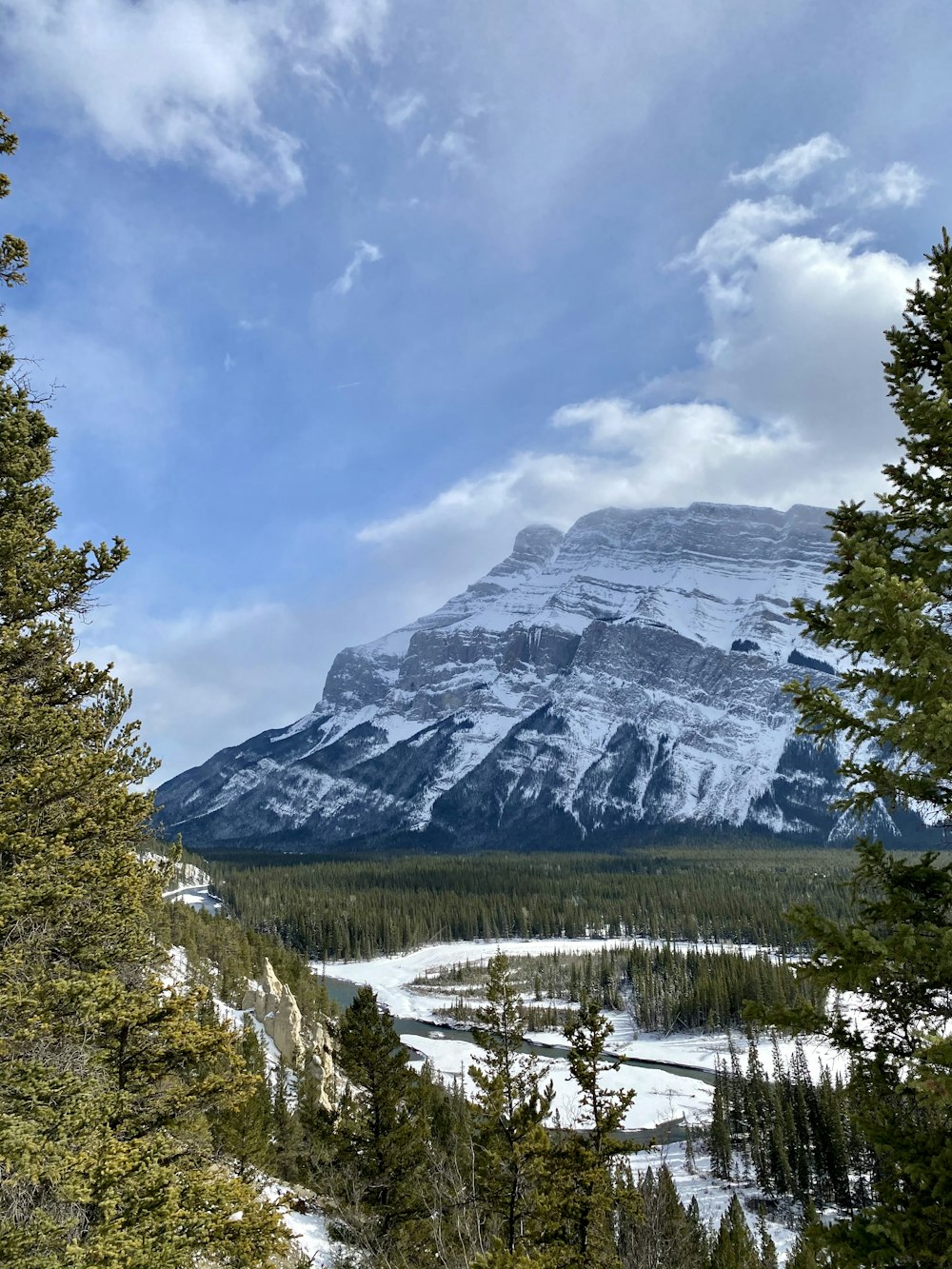 a snowy mountain with trees and a river below