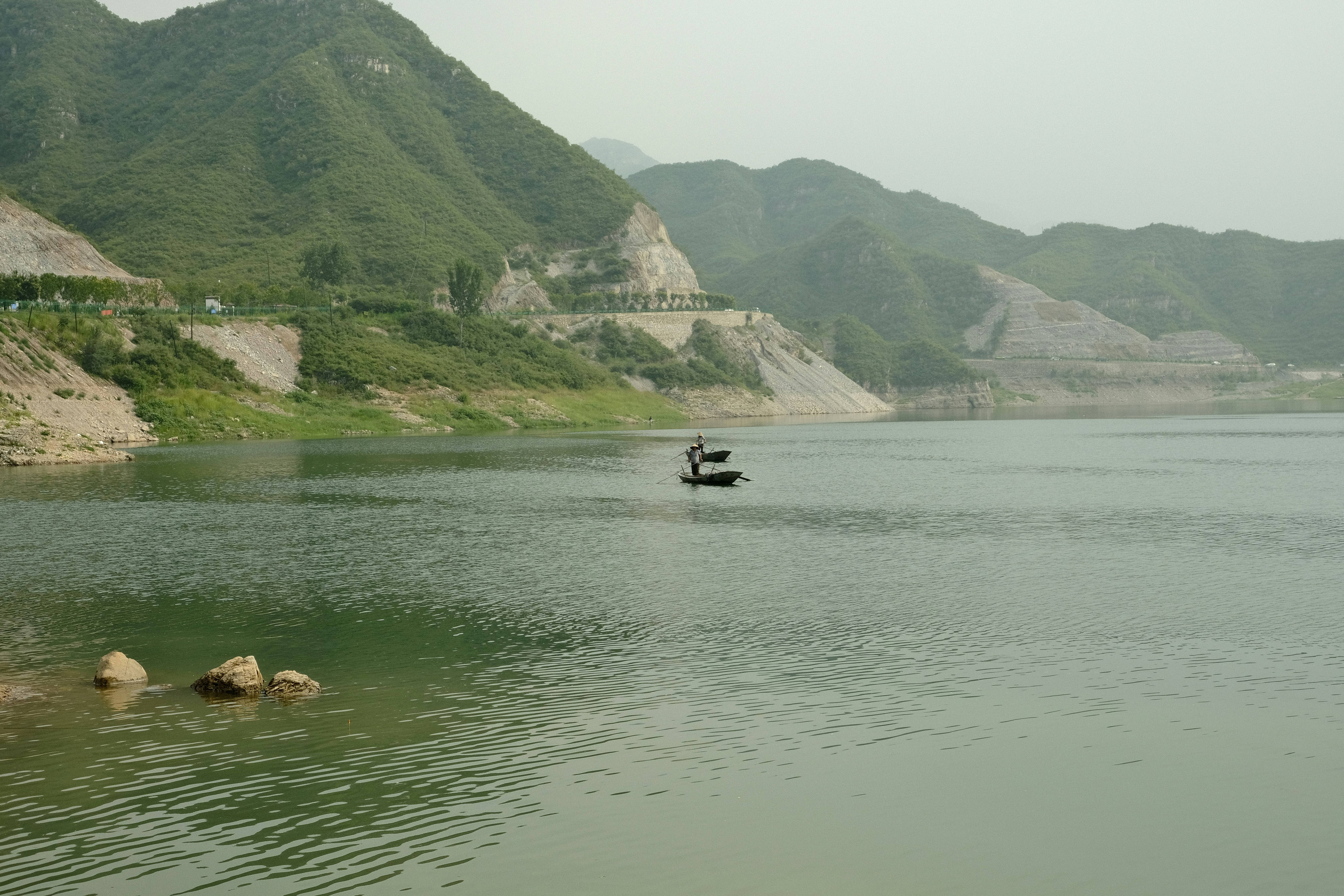 a person in a boat on a lake surrounded by hills