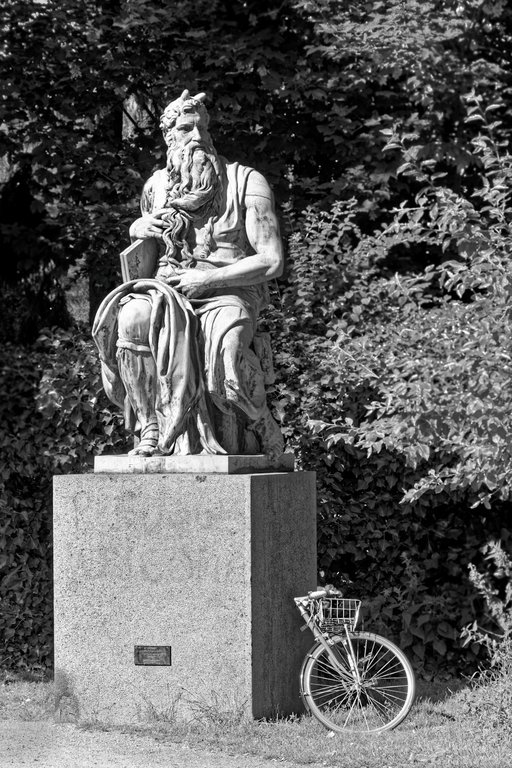 a statue of a person sitting on a stone pedestal