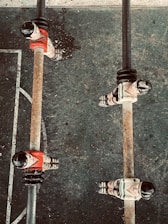 Several foosball players are positioned on metal rods on a foosball table. The players are wearing red and white uniforms, and the table surface has scuff marks indicating usage. The perspective is from above, capturing a section of the foosball field with visible white lines on a dark surface.