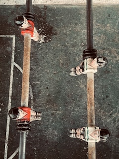 Several foosball players are positioned on metal rods on a foosball table. The players are wearing red and white uniforms, and the table surface has scuff marks indicating usage. The perspective is from above, capturing a section of the foosball field with visible white lines on a dark surface.