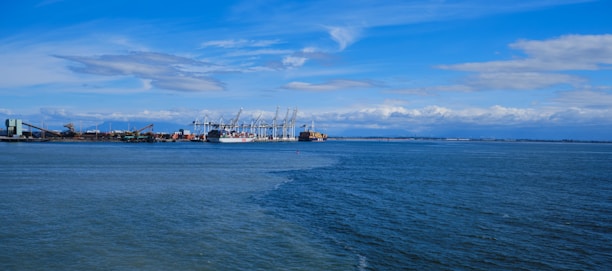 A panoramic view of a Saudi Arabian port with ships docked under a clear blue sky.